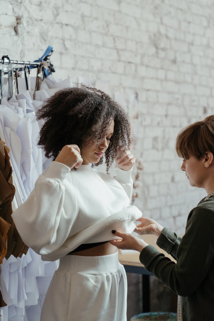 Fashion designer working with a model during a fitting session in a clothing atelier.